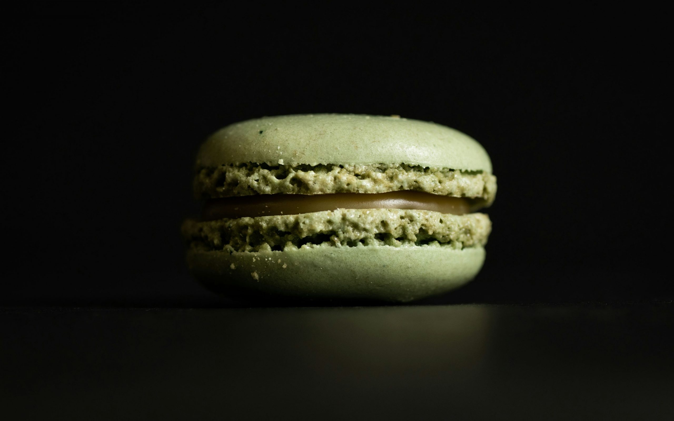 Cake Artistv Berlin Macaron Backkurse grüner Macaron vor schwarzem Hintergrund