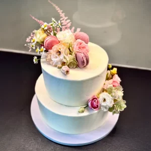 Zweistöckige Torte „Soft Bloom“ mit floraler Dekoration und Macarons – handgefertigt von Cake Artist Berlin