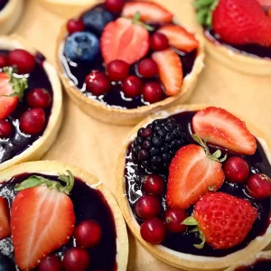 Fruchtige Tartelettes mit Beeren, handgebackene Mürbeteigböden mit glänzendem Fruchtspiegel und frischen Erdbeeren